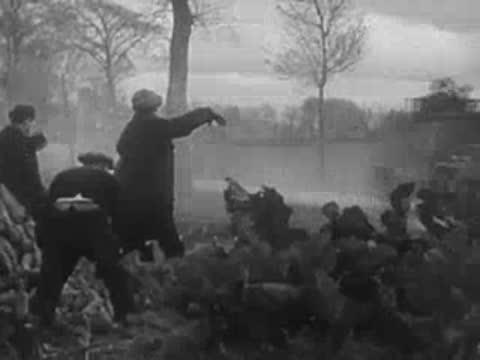 Civilians crouching by the roadside as military vehicles pass by.