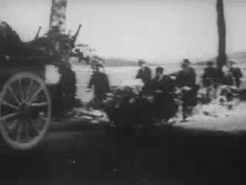 Soldiers in helmets carrying rifles and marching along a road.