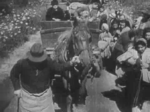 Refugees with horse-drawn cart and nuns walking along a road.