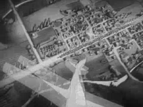 Aerial animation of an airplane symbol descending over a map of a town.