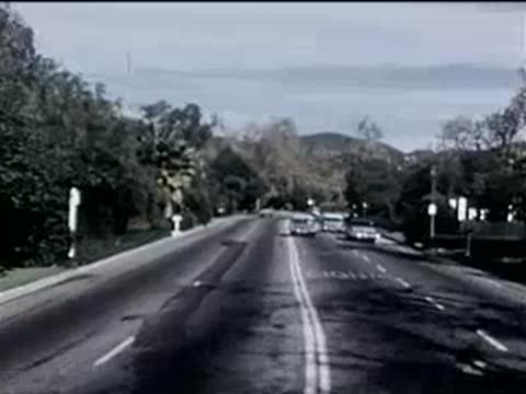Forward view from moving car driving down a multi-lane suburban road.
