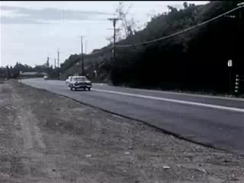 View of a road and passing cars from a moving vehicle's perspective.