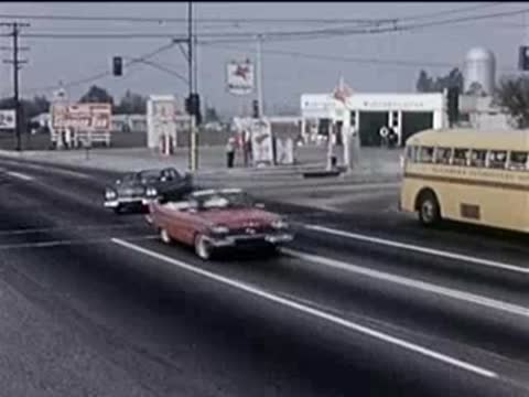 Cars driving on a multi-lane city street near a gas station.