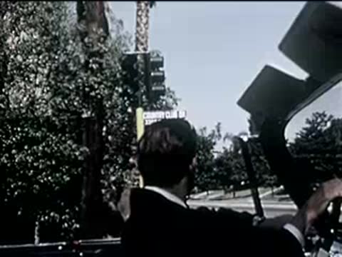 driver waiting at a red traffic light in an open-top car, 1950s
