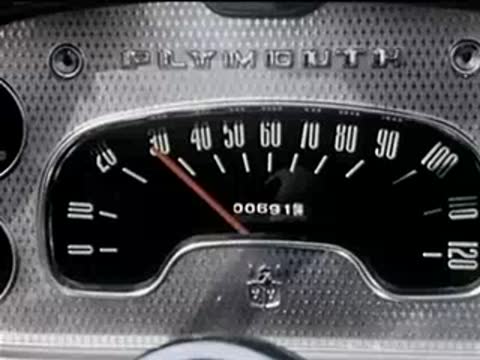 close-up of a car dashboard speedometer and steering wheel, 1950s