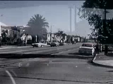 view from inside a car driving down a sunny suburban street, 1950s