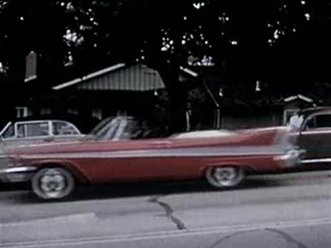 cars parked along a suburban residential street with houses, 1950s