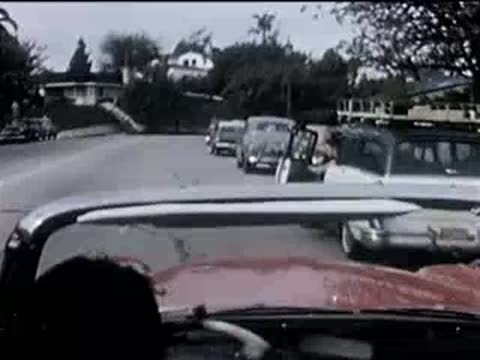 driver in a convertible turning onto a suburban residential street, 1950s