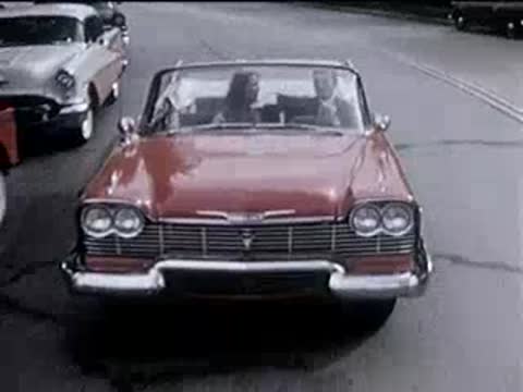 Front view of a red convertible driving forward on a street.