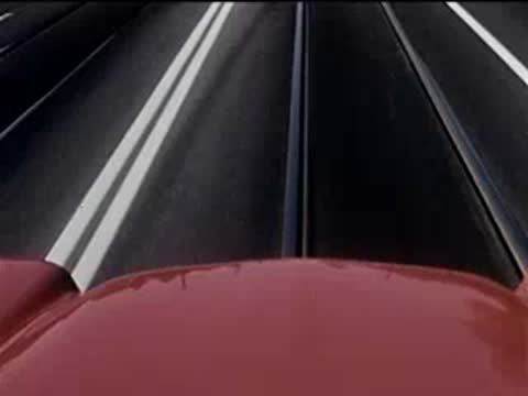 Low-angle shot from the hood of a red convertible driving down a city street.