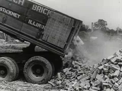 Dump truck unloading a pile of bricks on a construction site.