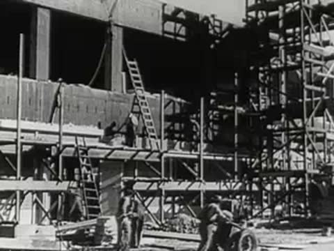 Workers on scaffolding constructing a large industrial building.