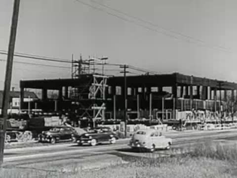 Cars driving past a commercial building under construction.