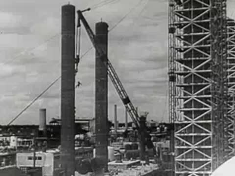 Construction cranes operating next to an industrial building.