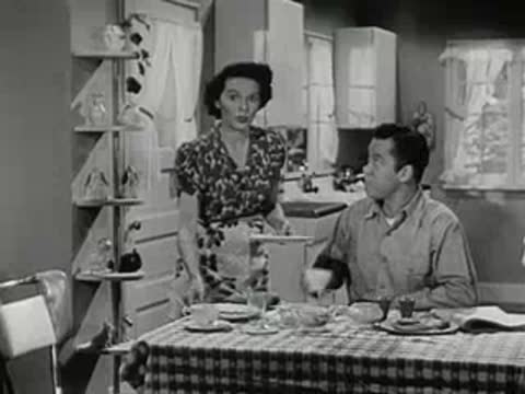 Woman serving a cup of coffee to a man at a table.