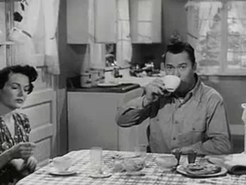 Man drinking coffee while a woman reads at the table.