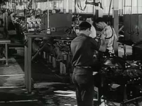 Workers operating machinery in an industrial manufacturing plant.
