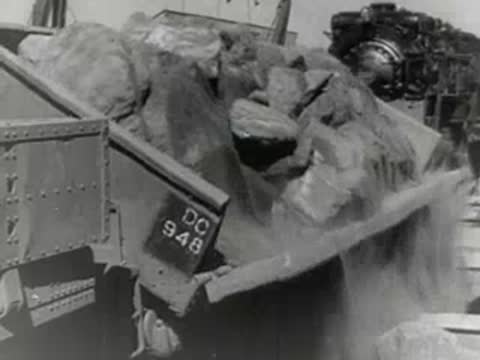 Freight cars dump material into a large industrial cargo ship hold.