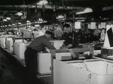 Workers in a manufacturing plant and a large crowd outside.