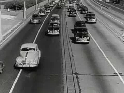 Crowd of people walking on a city street with cars driving.