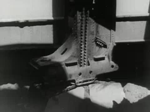 Industrial machinery crushes large rocks on an assembly line.
