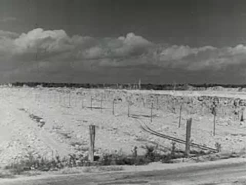 Open-pit mine with steam train on tracks; explosion in quarry.