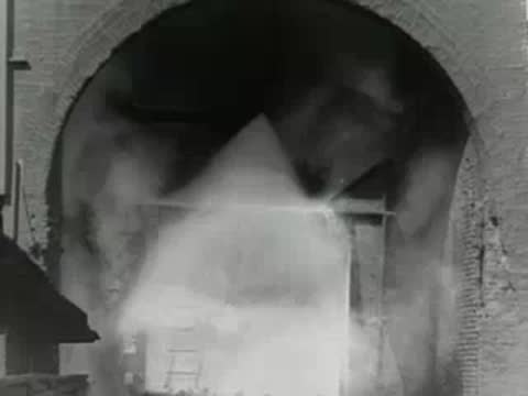 Steam and smoke vent from industrial structure inside factory complex, 1950s documentary.