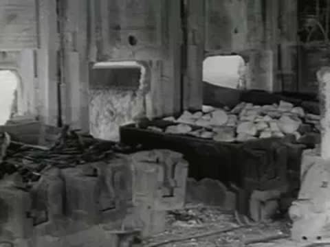 Industrial machinery loads and processes raw materials inside steel plant, 1950s documentary.