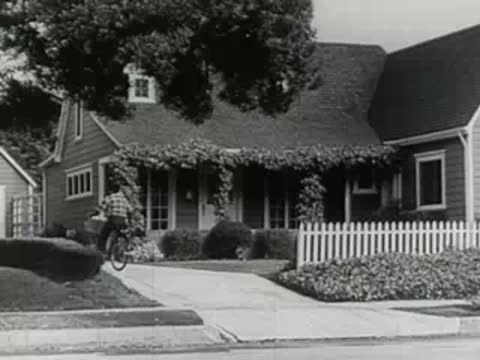 Static exterior view of a suburban residential house with lawn and trees.