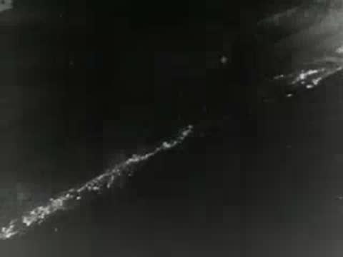 Molten metal pours and sparks fly inside industrial processing facility, 1950s.