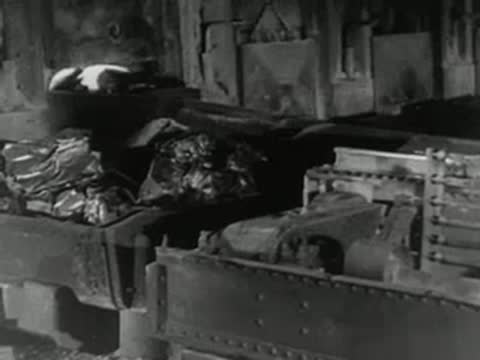 Heavy industrial machinery operates inside steel manufacturing plant, 1950s footage.