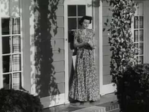 A woman in a floral dress walks out of the front door.