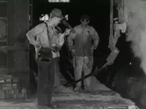 Workers operate equipment near molten metal pouring area inside steel plant, 1950s.