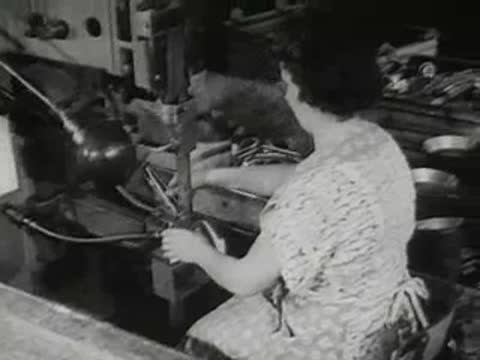 factory worker sorting and stacking finished metal pans, 1950s