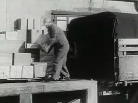 worker loading cardboard boxes into back of delivery truck at loading dock