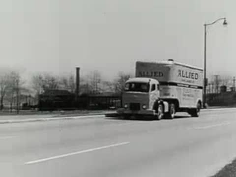 large semi-truck driving along paved city street, 1950s