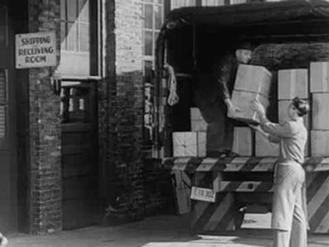 workers loading cargo boxes into back of delivery truck at shipping facility