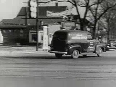 hardware supply delivery van driving along paved city street, 1950s