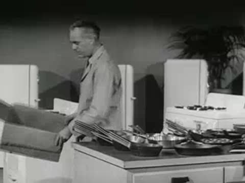hardware store clerk packing merchandise back into cardboard box, 1950s