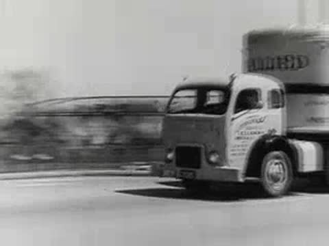 large semi-truck driving along paved city street, 1950s