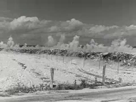 explosive mining operation with dust clouds over open pit quarry, 1950s