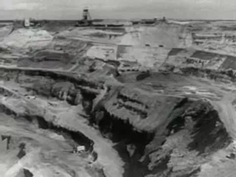 large mining excavator dumping excavated earth in open pit mine, 1950s