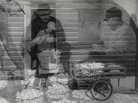 Men grading eggs on a farm and a worker pushing an egg cart outside