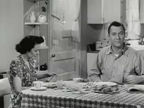 A woman and man eating breakfast together at a checkered tablecloth dining table