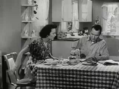 A man and woman eating breakfast, the woman getting up, and returning to the table