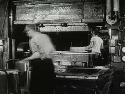 Factory worker operating a large industrial stamping machine.