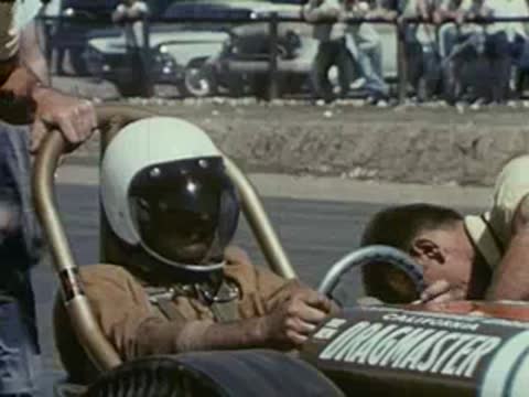 Driver in a helmet sitting in the cockpit of a dragster.