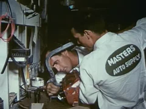 Two mechanics wearing Masters Auto Supply shirts working in a workshop.