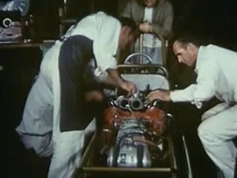 Mechanics installing parts onto a red engine in a drag car.