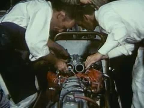 Mechanics working together on the engine of a custom car.